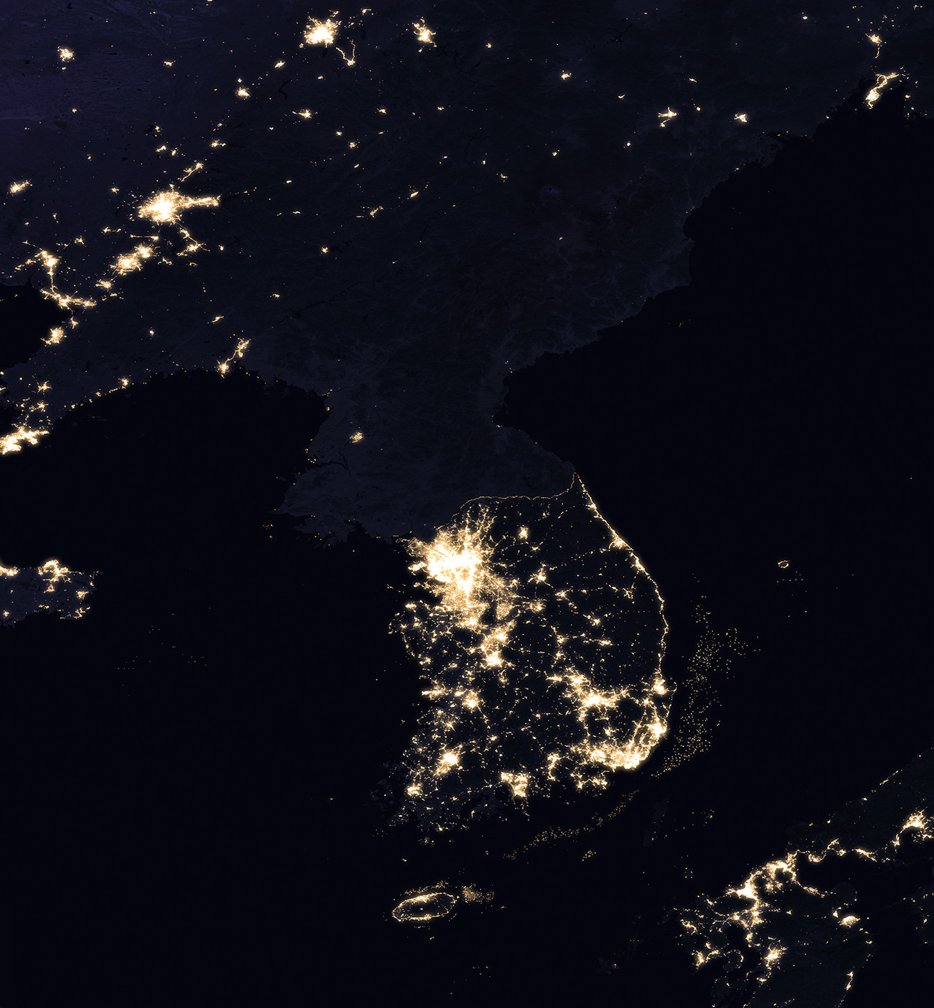 Satellite night view of the Korean peninsula. South Korea is densely lit; North Korea is almost entirely dark except for a small island of light at Pyongyang.